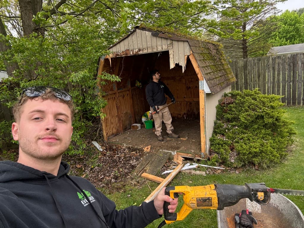 Evergreen crew demolishing a shed with power tools